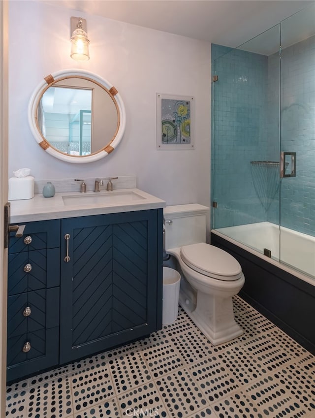 full bath with toilet, enclosed tub / shower combo, vanity, and tile patterned flooring