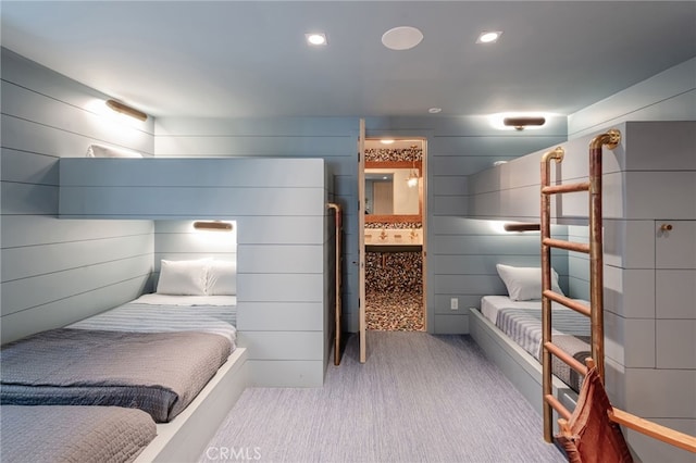 carpeted bedroom with wood walls and ensuite bath