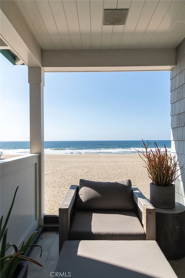 view of patio / terrace with a view of the beach, a balcony, and a water view
