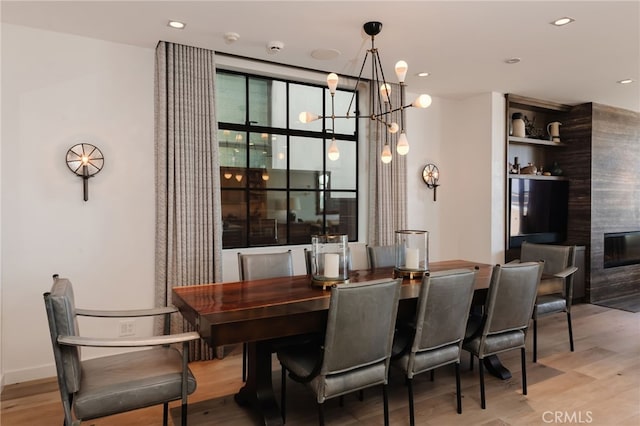 dining area with an inviting chandelier, a fireplace, wood finished floors, and recessed lighting