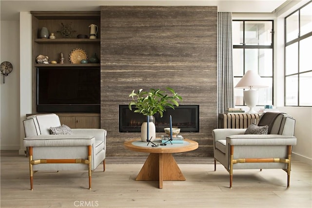 sitting room featuring baseboards, wood finished floors, and a high end fireplace