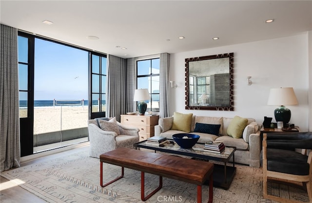 living area with light wood-style floors, expansive windows, a water view, and recessed lighting