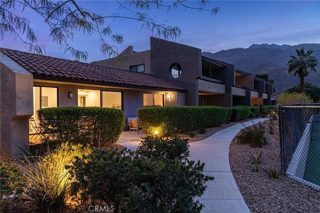 view of front of house featuring a tiled roof, fence, a mountain view, and stucco siding