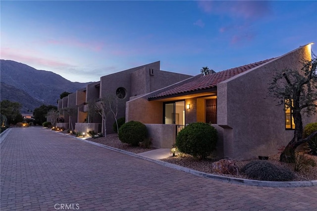 exterior space featuring stucco siding, a mountain view, and a tile roof