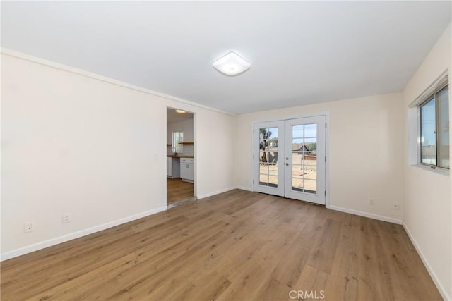 unfurnished room featuring french doors, light wood-style flooring, and baseboards