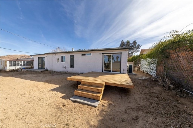 rear view of house featuring a fenced backyard, a deck, and stucco siding