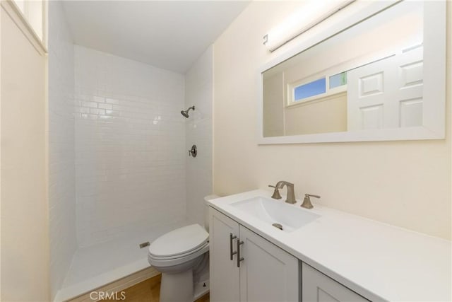 bathroom with tiled shower, vanity, and toilet