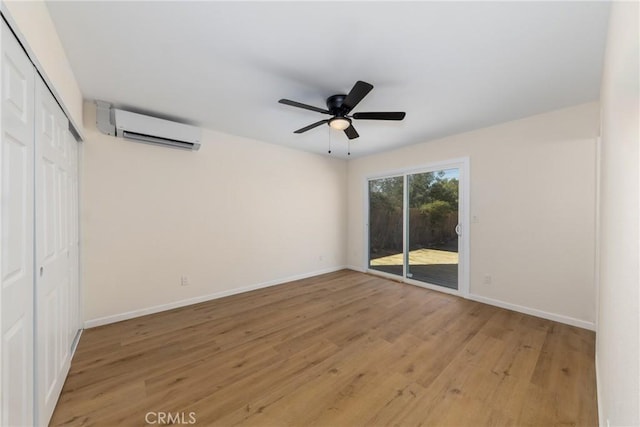 empty room featuring light wood-style floors, ceiling fan, baseboards, and an AC wall unit