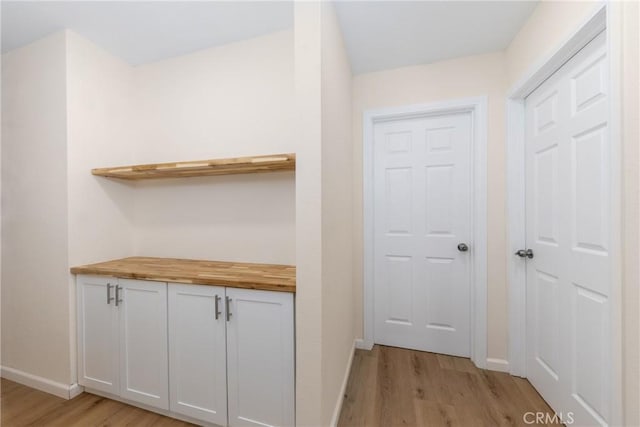 corridor featuring light wood-style floors and baseboards