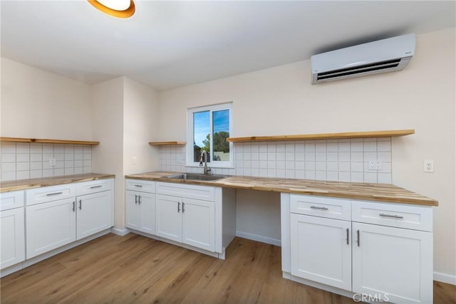 kitchen featuring open shelves, white cabinetry, a sink, wood counters, and a wall mounted air conditioner