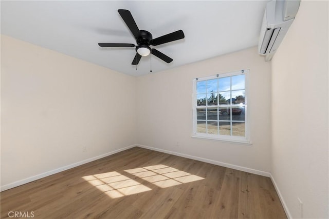 spare room featuring ceiling fan, baseboards, wood finished floors, and a wall mounted air conditioner