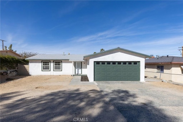 ranch-style home featuring fence, an attached garage, and stucco siding