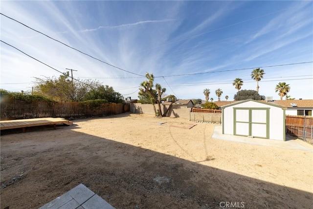 view of yard with a storage shed, a fenced backyard, and an outbuilding