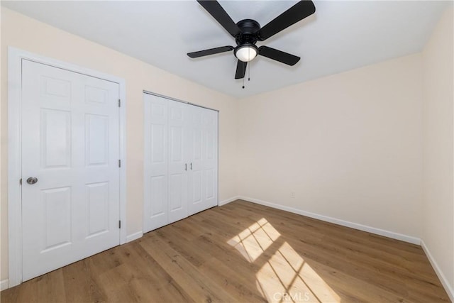 unfurnished bedroom with light wood finished floors, ceiling fan, baseboards, and a closet