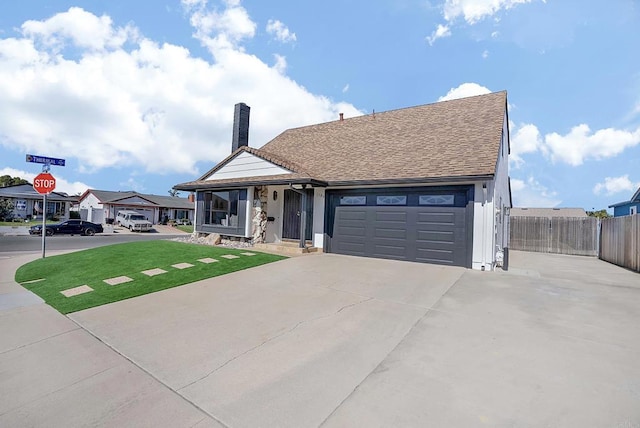 view of front of home featuring concrete driveway, a chimney, a residential view, an attached garage, and fence