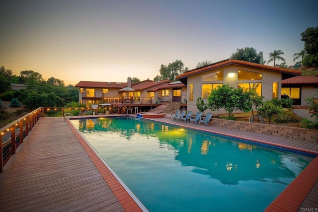 pool at dusk with a deck, a fenced in pool, and a patio