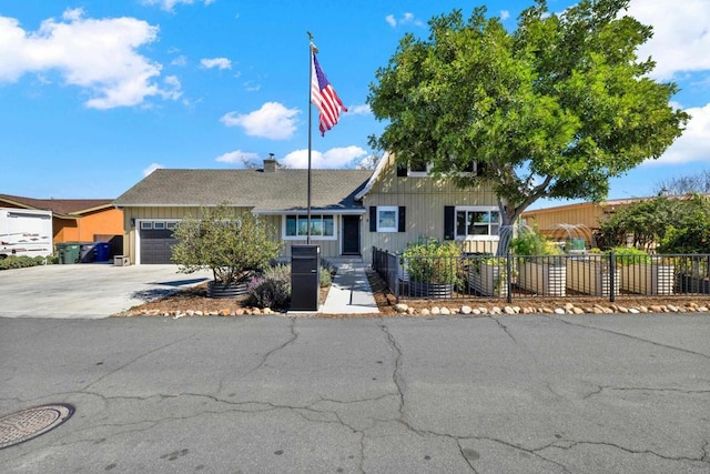 view of front of house with concrete driveway, an attached garage, and fence