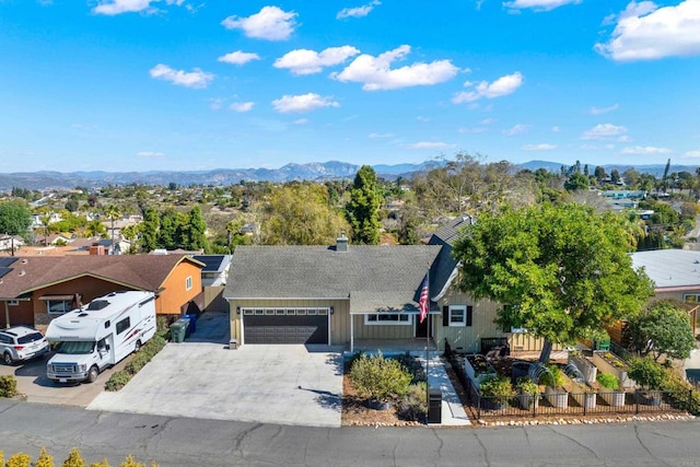 view of front of property with driveway, a fenced front yard, a residential view, an attached garage, and a mountain view