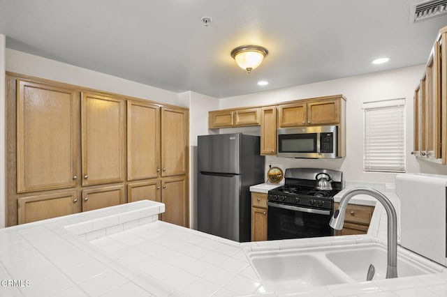 kitchen featuring visible vents, tile counters, stainless steel appliances, a sink, and recessed lighting