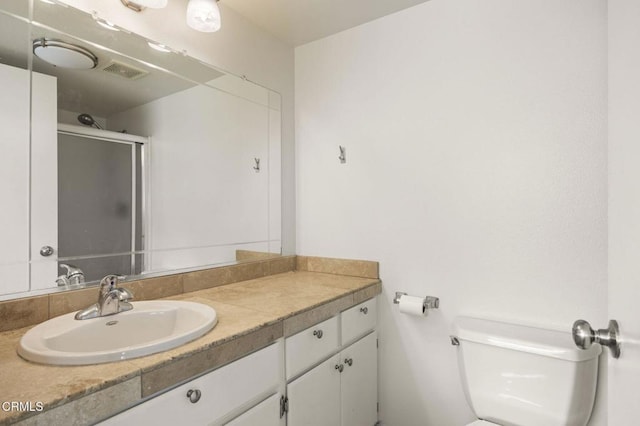 bathroom with toilet, an enclosed shower, visible vents, and vanity