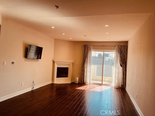 14242 Burbank Blvd Unit 103, Sherman Oaks, CA 91401 - unfurnished living room with dark wood-type flooring, recessed lighting, a fireplace, and baseboards
