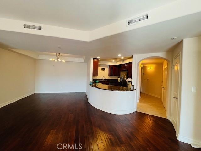 14242 Burbank Blvd Unit 103, Sherman Oaks, CA 91401 - unfurnished living room with wood-type flooring, arched walkways, baseboards, and a sink