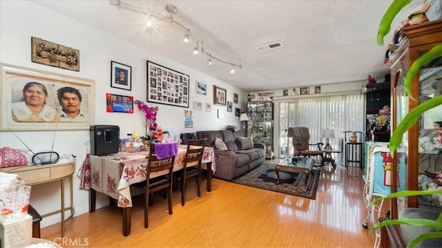 living area with a textured ceiling, visible vents, and light wood-style floors