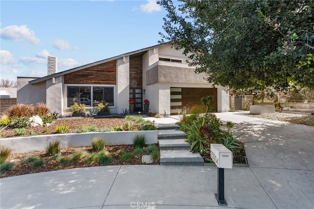 view of front of home with concrete driveway, a chimney, and stucco siding