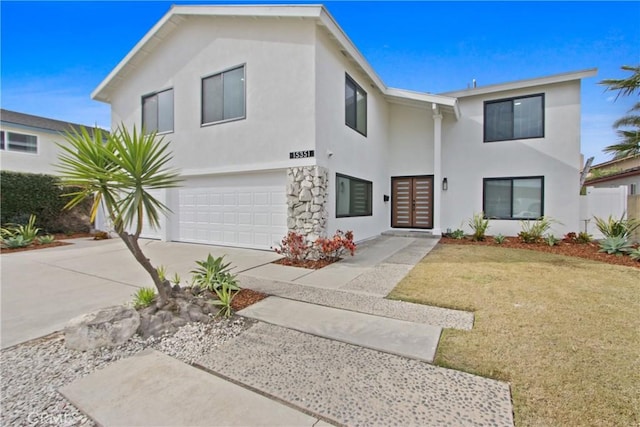 view of front facade featuring a garage, a front yard, concrete driveway, and stucco siding