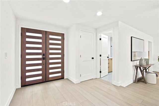 entryway with french doors, light wood-style flooring, and baseboards