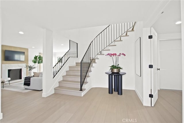 stairway with baseboards, a fireplace, wood finished floors, and recessed lighting