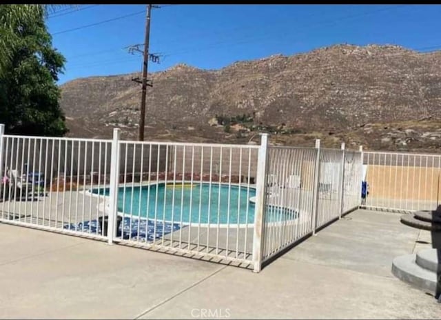 view of pool featuring a fenced in pool, a patio area, fence, and a mountain view