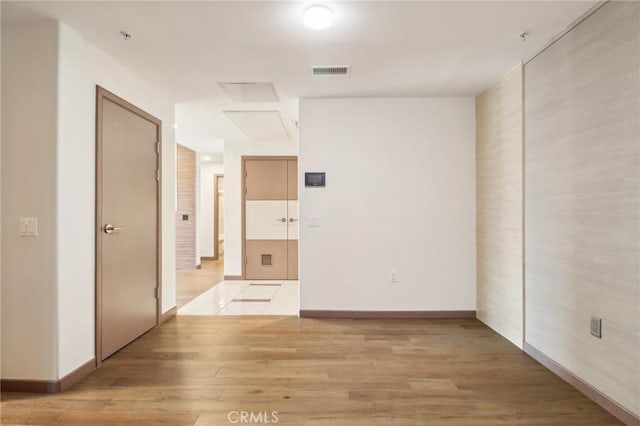 spare room with light wood finished floors, visible vents, and baseboards