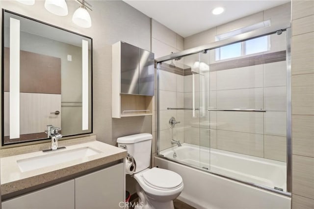 bathroom featuring vanity, toilet, and bath / shower combo with glass door