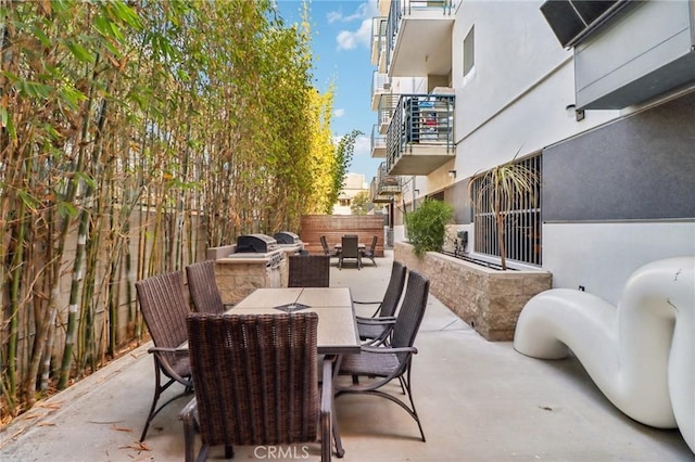 view of patio with outdoor dining space, exterior kitchen, and fence