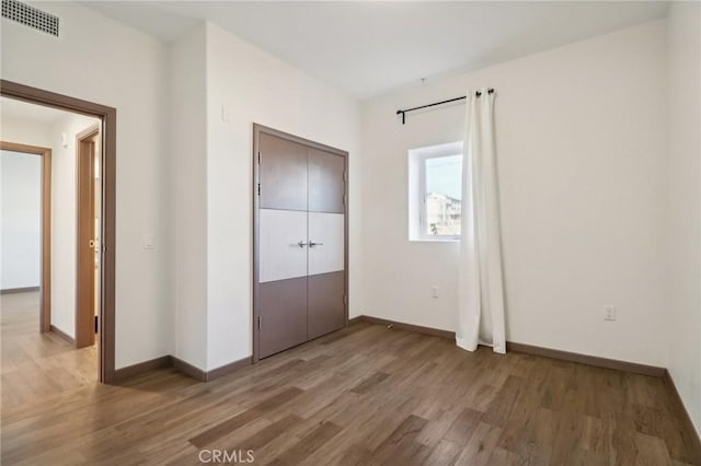 unfurnished bedroom with visible vents, baseboards, and wood finished floors