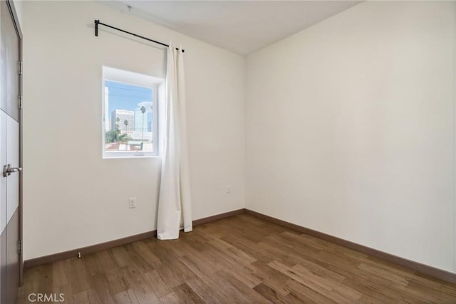 empty room with baseboards and wood finished floors