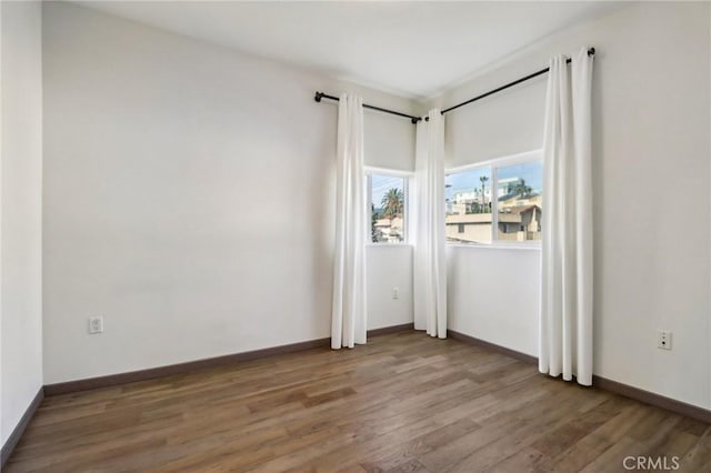 spare room featuring baseboards and wood finished floors