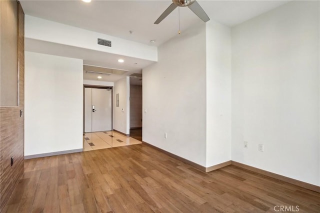 empty room featuring light wood-type flooring, baseboards, visible vents, and a ceiling fan