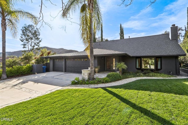 view of front of house featuring a mountain view, a garage, driveway, roof with shingles, and a front lawn