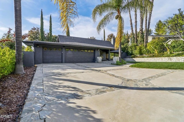 view of front of home with a garage, a chimney, and concrete driveway