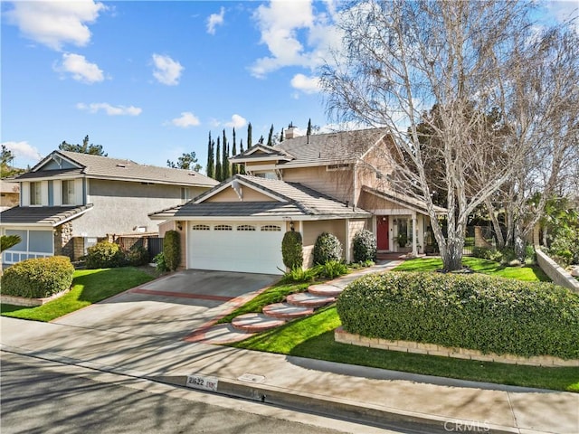 view of front of house with driveway, an attached garage, and a tile roof