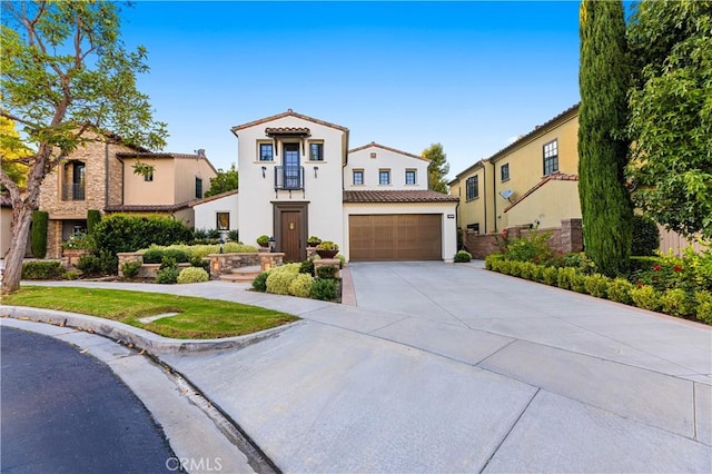 mediterranean / spanish-style house featuring a garage, driveway, a tiled roof, a residential view, and stucco siding