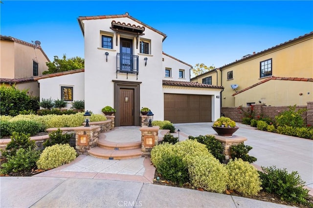 mediterranean / spanish home featuring an attached garage, a tile roof, concrete driveway, and stucco siding