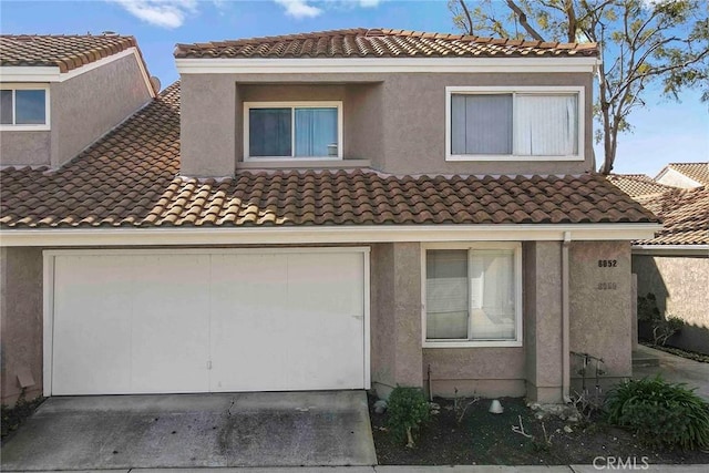 view of front of house featuring concrete driveway, a tiled roof, and stucco siding