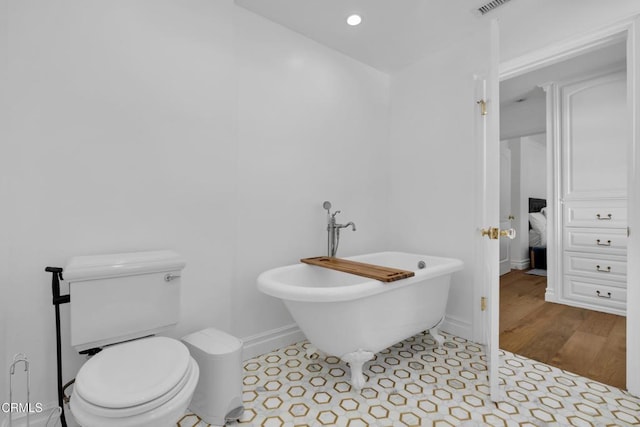 ensuite bathroom featuring baseboards, connected bathroom, toilet, tile patterned flooring, and a freestanding bath