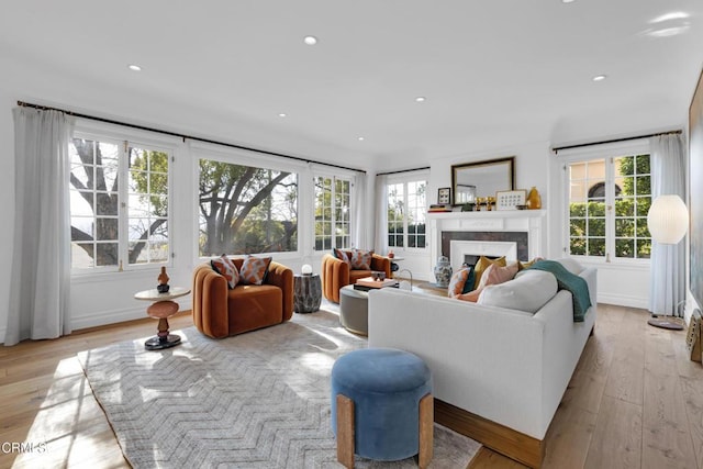 living area featuring light wood-style floors, recessed lighting, a fireplace, and plenty of natural light