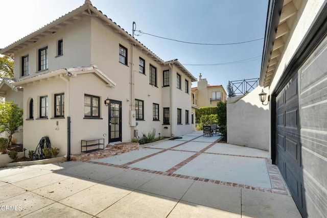 exterior space featuring a patio area, a tiled roof, and stucco siding