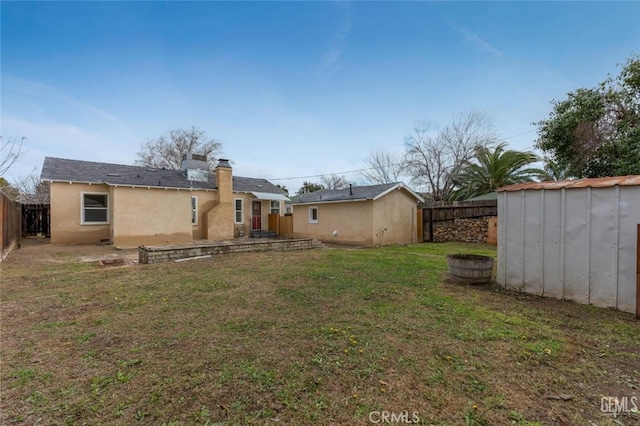 rear view of property with a fenced backyard, an outbuilding, a yard, a shed, and stucco siding