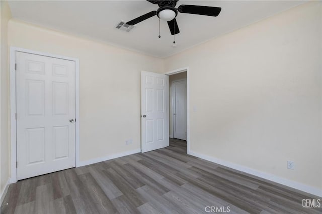 unfurnished bedroom featuring a ceiling fan, wood finished floors, visible vents, and baseboards